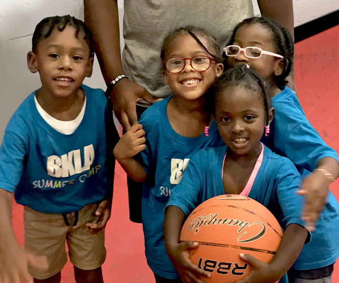 group of kids smiling holding basketballs