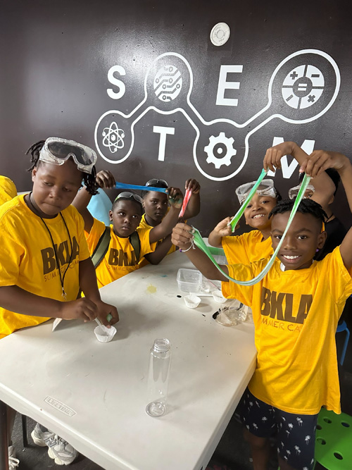 Summer Camp Kids playing with slime in STEM, smiling and having fun